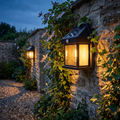 Farol solar LED montado en una pared de jardín y encendido al atardecer