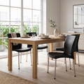 Sillas apilables negras con patas metálicas en uso alrededor de una mesa de comedor