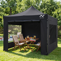 Gazebo plegable negro con paredes armado sobre el césped en una reunión al aire libre